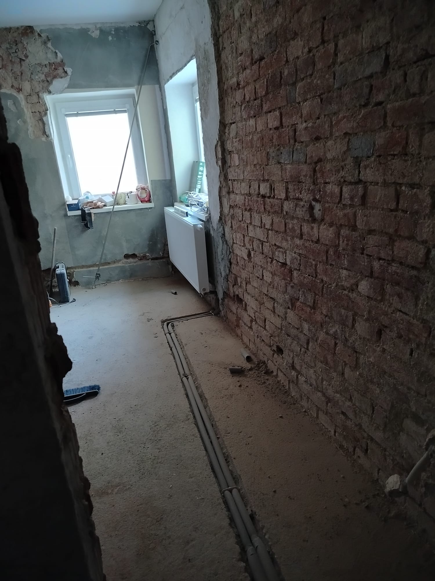 Rekonštruovaná miestnosť s novým radiátorom a rozvodmi v podlahe